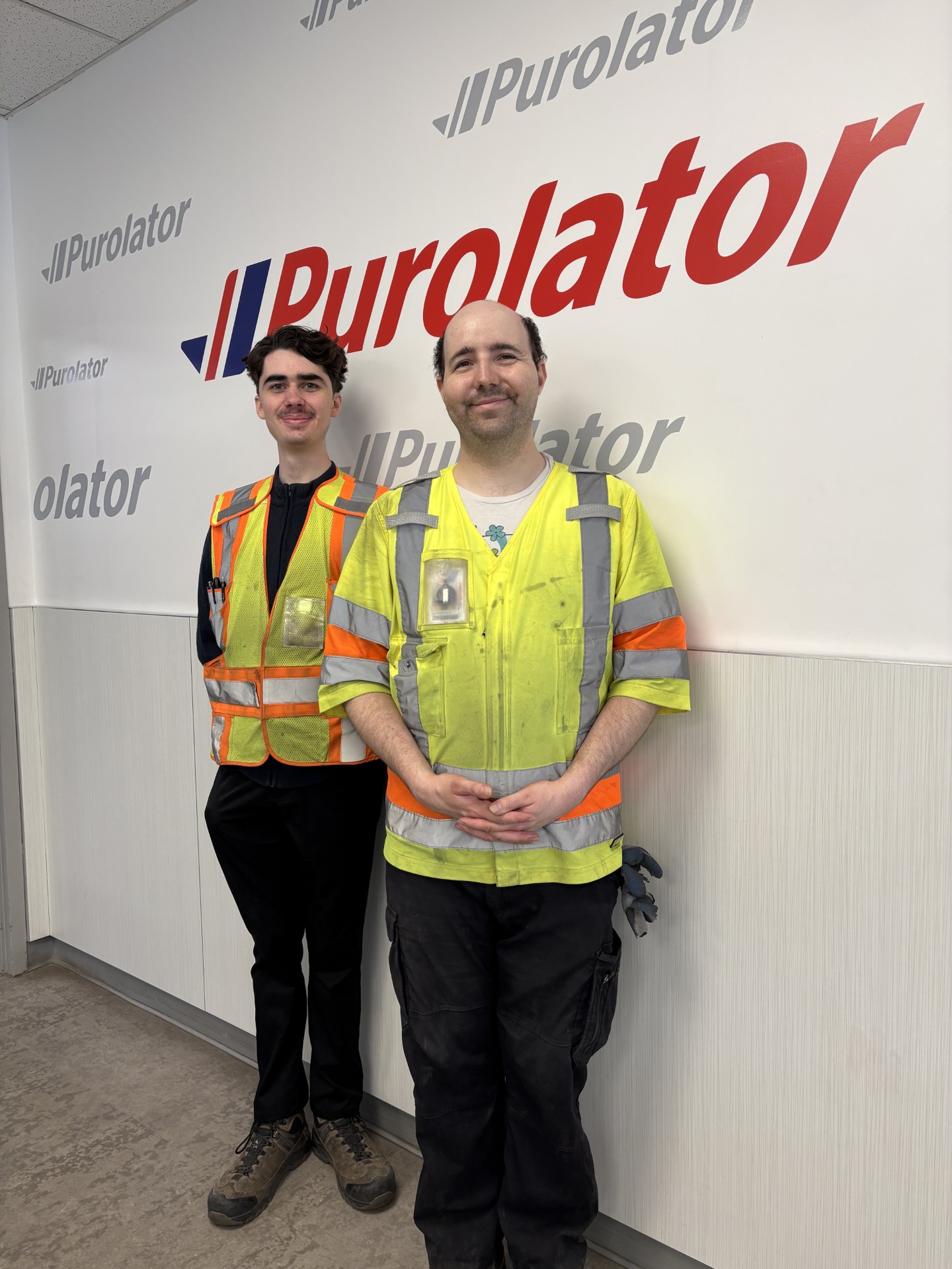 Gabe and Dominique standing in front of Purolator sign